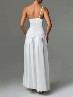 a woman in a long white dress is looking down at her back and has her hands on her hips