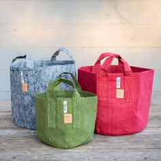 three different colored bags sitting next to each other on a wooden table with a white wall in the background