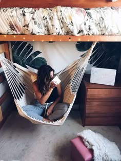 a woman sitting in a hammock drinking coffee