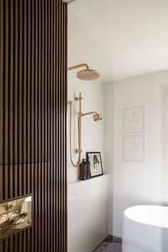 a white bath tub sitting next to a wooden shower head mounted on the side of a wall