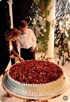 a man and woman standing in front of a large cake