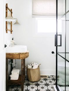 a bathroom with black and white tile flooring and a wooden sink vanity in the corner