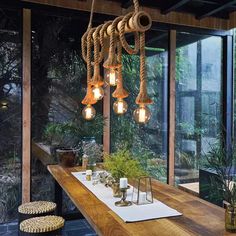 a long table with some lights hanging from it's sides and plants on the other side