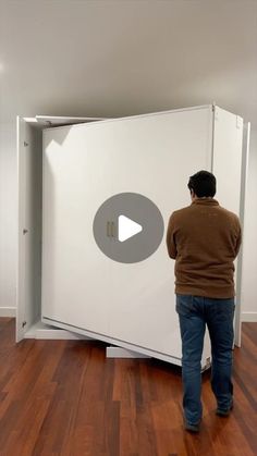 a man standing in front of a white box on top of a hard wood floor