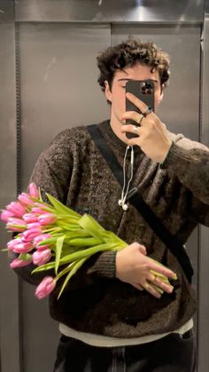 a man taking a selfie in front of a mirror with pink tulips