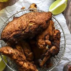 fried chicken in a wire basket with lemons and ketchup on the side