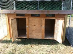 a chicken coop built into the side of a fenced in area with doors open