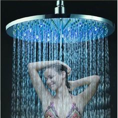 a woman in a bathing suit standing under a shower head with water pouring from it