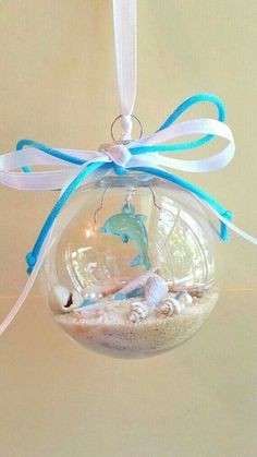 a glass ornament with a dolphin in the ocean inside it on a white ribbon