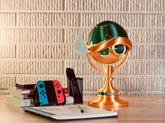 a desk with a book, pen and game controller on it next to a golden trophy