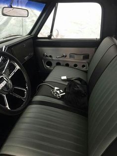 the interior of an old car with black leather seats and steering wheel, in front of snow covered mountains