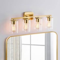 a bathroom vanity with three lights and a mirror on the wall in front of it