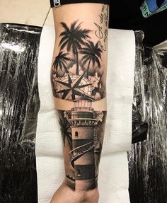 a man's arm with a lighthouse and palm trees on it