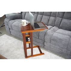 a laptop computer sitting on top of a wooden table in front of a gray couch