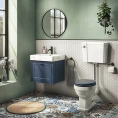 a bathroom with a toilet, sink, mirror and rug on the floor in front of it