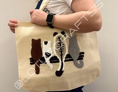 a woman holding a tote bag with three cats on it