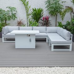 a white couch sitting on top of a wooden floor next to a plant filled wall