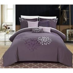 a bed with purple comforters and pillows