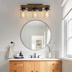 a bathroom vanity with a round mirror above it and two lights on either side of the sink