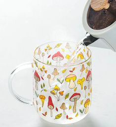 a glass mug with mushrooms on it being filled with coffee