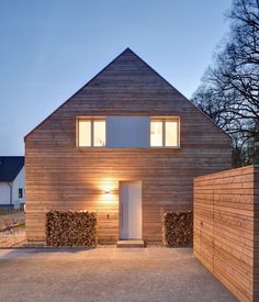 a house that is made out of wood and has windows on the front, with light coming from inside