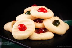 some cookies with jelly on them sitting on a black plate