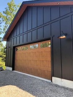 two garage doors are open on the side of a large black building with trees in the background