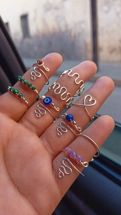 a person holding out their hand with five different rings on it and the word love spelled in cursive writing