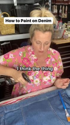 a woman in pink shirt cutting jeans with scissors and writing on the bottom right corner