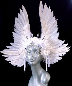 a white mannequin headpiece with feathers on it's head and tassels