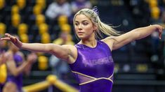 a woman in a purple leotard doing gymnastics