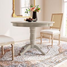 a white table with two chairs and a vase filled with flowers sitting on top of it