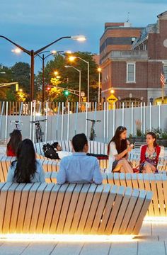 people sitting on benches in the city at night