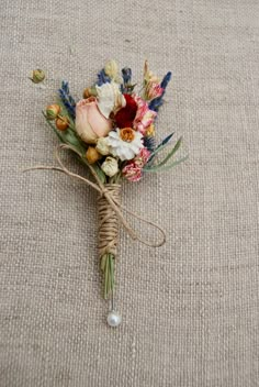 a boutonniere is adorned with flowers and greenery on a linen surface