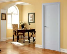 an empty room with yellow walls and wooden flooring is pictured in this image, there are two chairs at the table