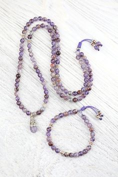 We are so excited to introduce our DharmaShop exclusive Super Seven Mala! Hand strung here in Detroit with genuine Super Seven beads from Brazil and a faceted Amethyst gemstone pendant from Nepal. Super Seven is a rare mineral made from a blend of seven crystals including: Amethyst, Clear Quartz, Smoky Quartz, Cacoxenite, Rutile, Geothite, and Lepidocrocite. This incredibly powerful stone combines the healing properties of all seven crystals! Super Seven is believed to energize and heal all seve Spiritual Faceted Bead Gemstones For Gift, Spiritual Faceted Beads Gemstones As Gift, Amethyst Crystal Necklace With Faceted Beads As Gift, Amethyst Round Beads Jewelry For Meditation, Spiritual Amethyst Necklace With Faceted Beads, Spiritual Lavender Jewelry With Faceted Beads, Lavender Spiritual Jewelry With Faceted Beads, Spiritual Fluorite Jewelry For Meditation, Healing Purple Crystal Necklaces With Faceted Beads