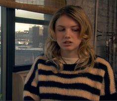 a woman standing in front of a window with her eyes closed