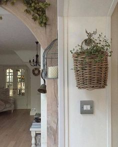 a basket hanging on the wall next to a light switch in a living room with wood floors and white walls