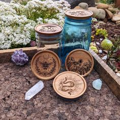 three mason jars sitting on top of a table next to some rocks and flowers in the background