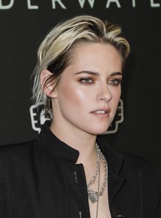 a woman with blonde hair wearing a black shirt and silver necklace on the red carpet