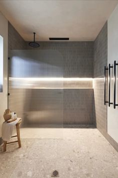 a bathroom with a toilet, sink and shower in it's center wall that is made out of gray tiles