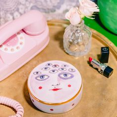 a pink phone sitting on top of a table next to a vase with flowers in it