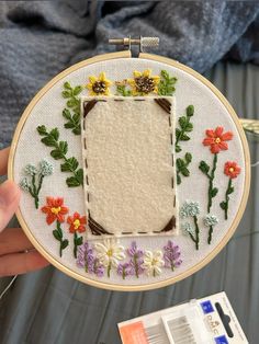 a person holding up a small embroidered frame