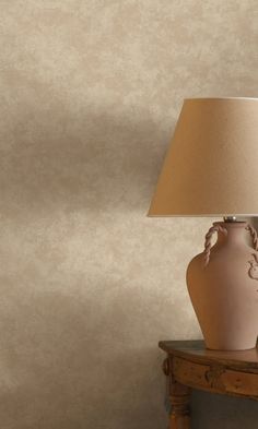 a table lamp sitting on top of a wooden table next to a white vase with an intricate design