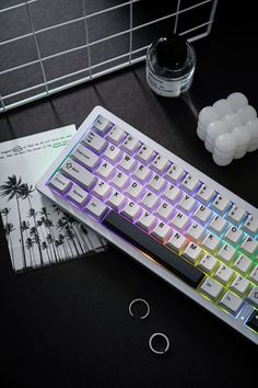 a computer keyboard sitting on top of a desk next to some papers and pens with palm trees in the background