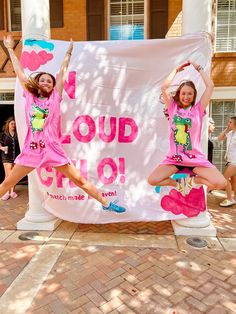 two girls in pink dresses are jumping on a sign