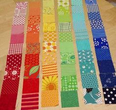 several strips of colorful fabric laid out on a wooden table top with polka dots and flowers