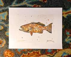 a card with a fish on it sitting on top of a carpeted floor next to a rug