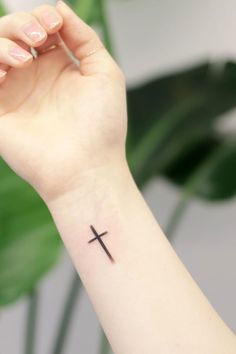 a woman's arm with a small cross tattoo on the left side of her wrist