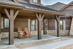 a wooden chair sitting on top of a porch next to a stone building with windows